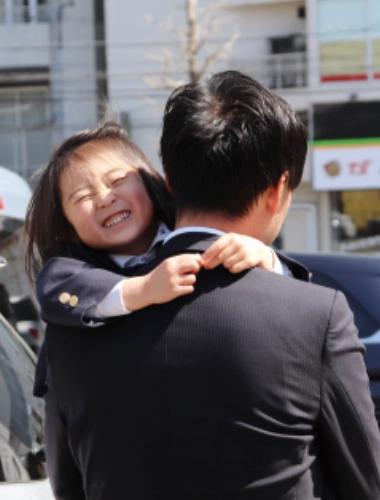スーツのパパに抱えられる子どもの写真